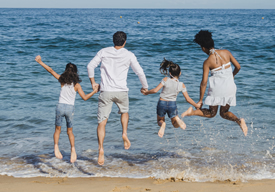 Photo of family leaping into water at the beach.